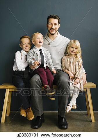 Stock Image - Father sitting with his three children. Fotosearch