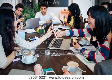 Stock Image - Female and male business team meeting at cafe table. Fotosearch