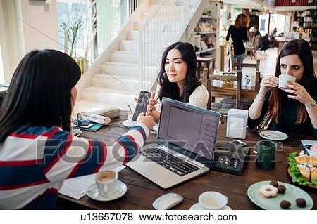 Female business team meeting while having working lunch at cafe table View Large Photo Image Stock Photo - Female business team meeting while having working lunch at cafe table. Fotosearch
