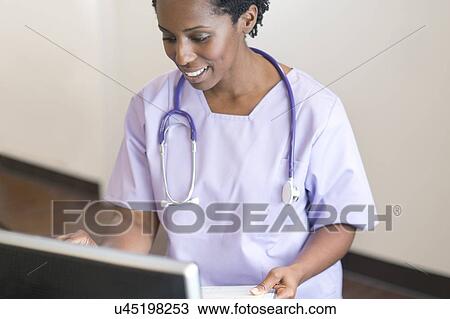 Female nurse using computer, smiling. View Large Photo Image Stock Image - Female nurse using computer, smiling.. Fotosearch