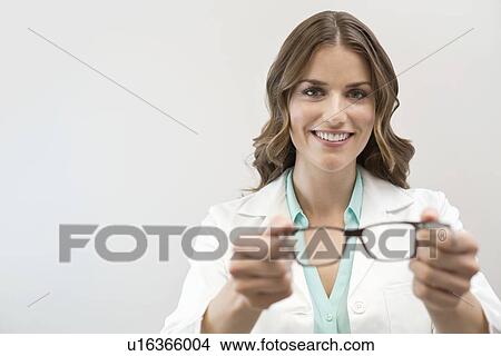 Picture - Female optician holding glasses.. Fotosearch