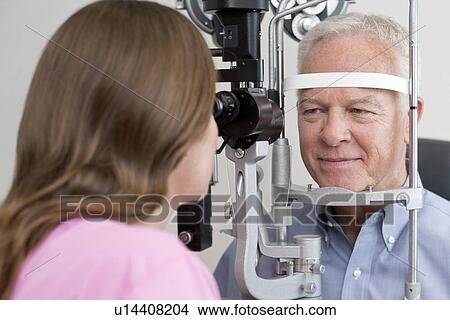 Female optician testing senior man's eyesight. View Large Photo Image Picture - Female optician testing senior man's eyesight.. Fotosearch