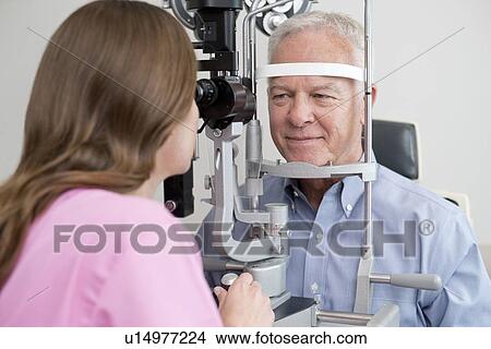 Picture - Female optician testing senior man's eyesight.. Fotosearch