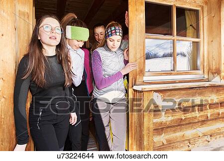 Picture - Four teenage girl skiers looking out from cabin doorway, Tyrol, Styria, Austria. Fotosearch