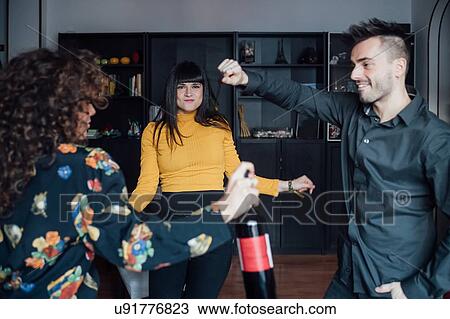 Stock Image - Friends celebrating, dancing at home. Fotosearch