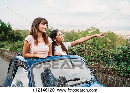 Stock Image - Friends enjoying view in car sunroof, Florence, Toscana, Italy. Fotosearch