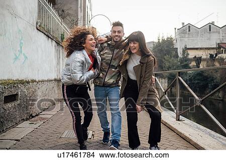 Picture - Friends laughing and playing by river, Milano, Lombardia, Italy. Fotosearch