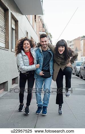 Stock Photography - Friends laughing and playing on pavement, Milano, Lombardia, Italy. Fotosearch