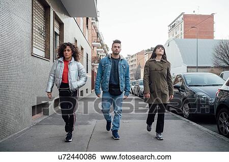 Stock Photograph - Friends play acting catwalk on pavement, Milano, Lombardia, Italy. Fotosearch