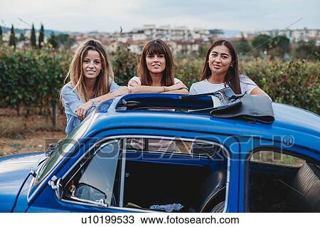 Stock Image - Friends posing beside car in countryside, Florence, Toscana, Italy. Fotosearch