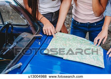 Friends reading route map on car bonnet View Large Photo Image Stock Photo - Friends reading route map on car bonnet. Fotosearch