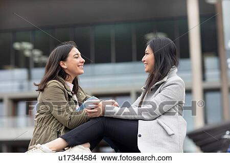 Friends relaxing in front of building View Large Photo Image Picture - Friends relaxing in front of building. Fotosearch