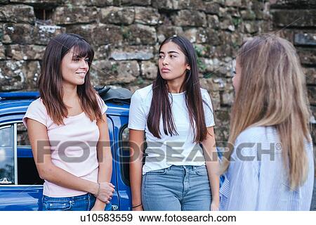 Stock Photo - Friends talking beside car in countryside. Fotosearch
