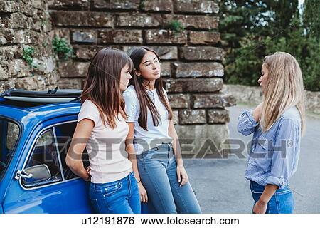 Stock Photograph - Friends talking beside car in countryside. Fotosearch