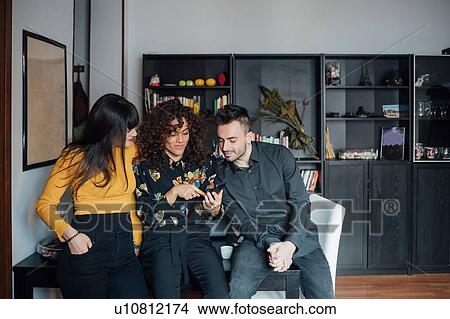Friends using smartphone at home View Large Photo Image Picture - Friends using smartphone at home. Fotosearch
