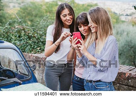 Stock Image - Friends using smartphone in countryside. Fotosearch