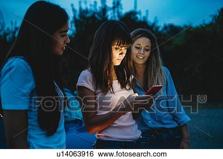 Stock Photograph - Friends using smartphone in countryside. Fotosearch