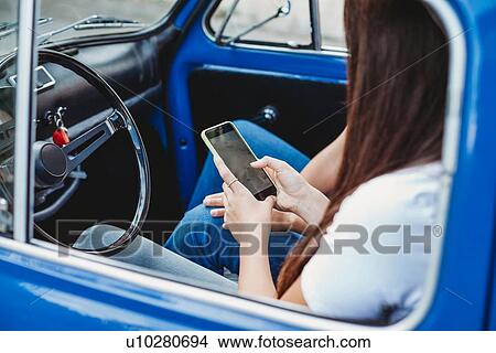 Picture - Friends using smartphone inside car. Fotosearch