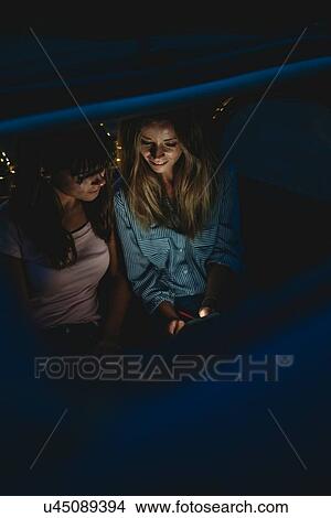 Picture - Friends using smartphone inside car. Fotosearch