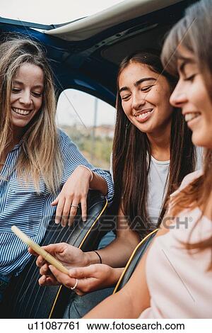 Friends using smartphone inside car View Large Photo Image Stock Image - Friends using smartphone inside car. Fotosearch