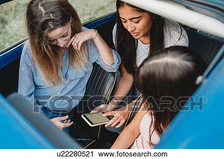 Friends using smartphone inside car View Large Photo Image Stock Image - Friends using smartphone inside car. Fotosearch