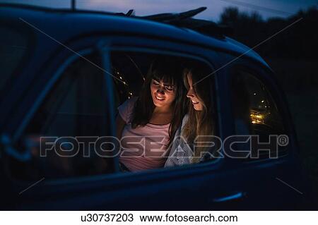 Friends using smartphone inside car View Large Photo Image Stock Image - Friends using smartphone inside car. Fotosearch