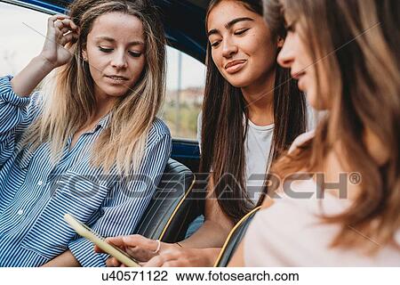 Friends using smartphone inside car View Large Photo Image Stock Image - Friends using smartphone inside car. Fotosearch