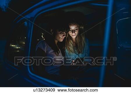 Friends using smartphone inside car View Large Photo Image Stock Photo - Friends using smartphone inside car. Fotosearch