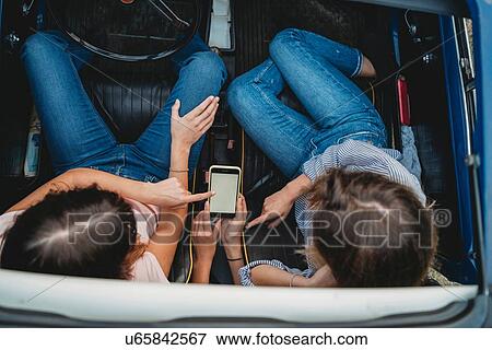 Friends using smartphone inside car View Large Photo Image Stock Photo - Friends using smartphone inside car. Fotosearch