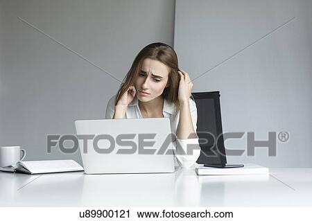 Stock Image - Frustrated businesswoman working at laptop. Fotosearch