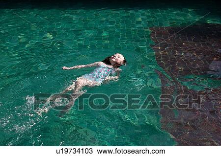 Stock Image - Girl floating in pool. Fotosearch