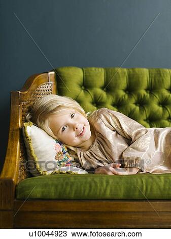 Stock Image - Girl lying on green sofa. Fotosearch