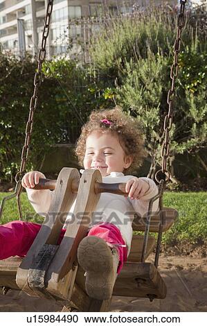 Stock Image - Girl on swing in city park. Fotosearch