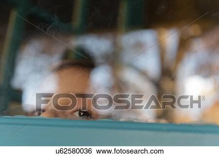 Girl peering through window View Large Photo Image Stock Photograph - Girl peering through window. Fotosearch