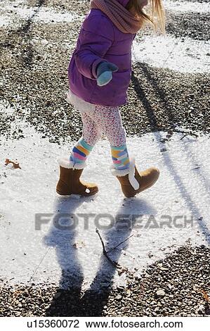 Stock Image - Girl wearing purple coat walking on snow. Fotosearch