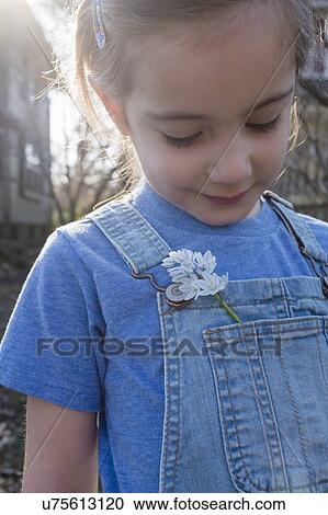 Stock Image - Girl with flower in overalls pocket. Fotosearch