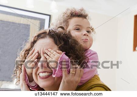 Girl with her hands covering her mother's eyes View Large Photo Image Stock Photo - Girl with her hands covering her mother's eyes. Fotosearch