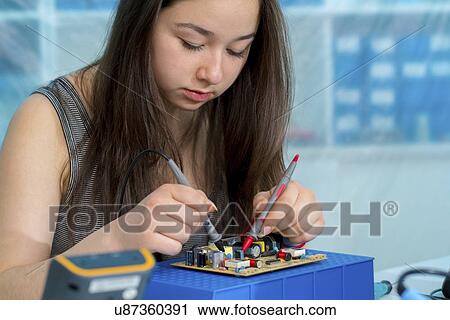 Stock Image - Girl working on electronics project.. Fotosearch