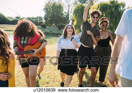 Stock Photo - Group of friends dancing, playing guitar in park. Fotosearch
