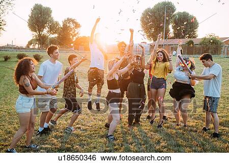 Group of friends dancing, playing with confetti in park View Large Photo Image Stock Photograph - Group of friends dancing, playing with confetti in park. Fotosearch