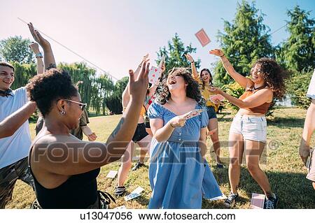 Group of friends dancing, throwing playing cards into air in park View Large Photo Image Stock Photograph - Group of friends dancing, throwing playing cards into air in park. Fotosearch