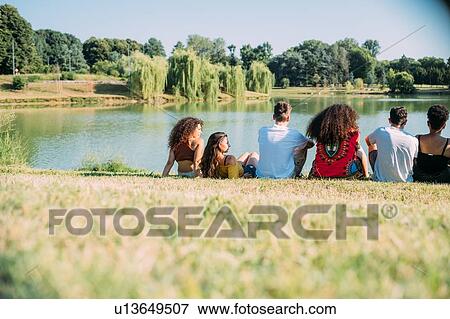Stock Photo - Group of friends enjoying view of lake in park. Fotosearch