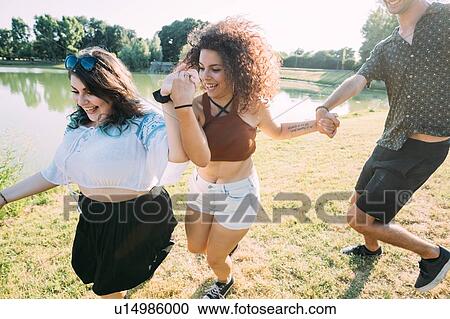 Stock Image - Group of friends having fun by lake. Fotosearch