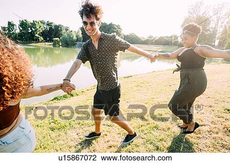 Stock Image - Group of friends having fun by lake. Fotosearch