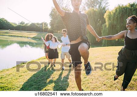Stock Image - Group of friends having fun by lake. Fotosearch