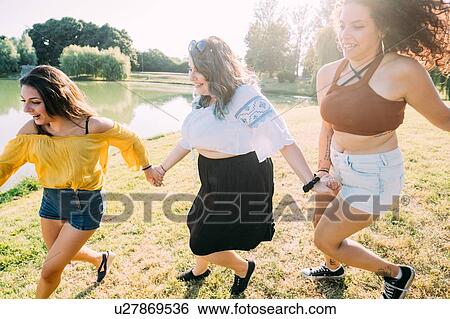 Stock Photograph - Group of friends having fun by lake. Fotosearch