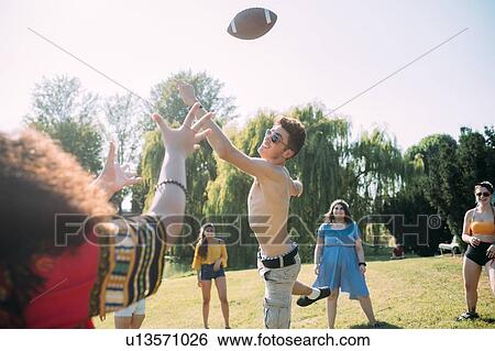 Group of friends playing football in park View Large Photo Image Stock Photograph - Group of friends playing football in park. Fotosearch