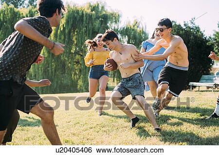 Group of friends playing football in park View Large Photo Image Stock Photograph - Group of friends playing football in park. Fotosearch
