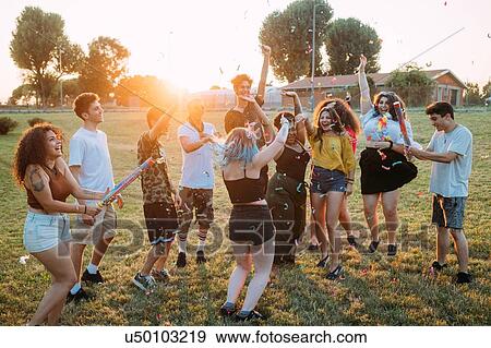 Group of friends playing with confetti in park View Large Photo Image Stock Photo - Group of friends playing with confetti in park. Fotosearch