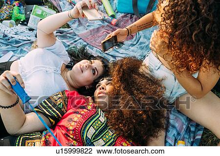 Stock Image - Group of friends relaxing at picnic in park. Fotosearch